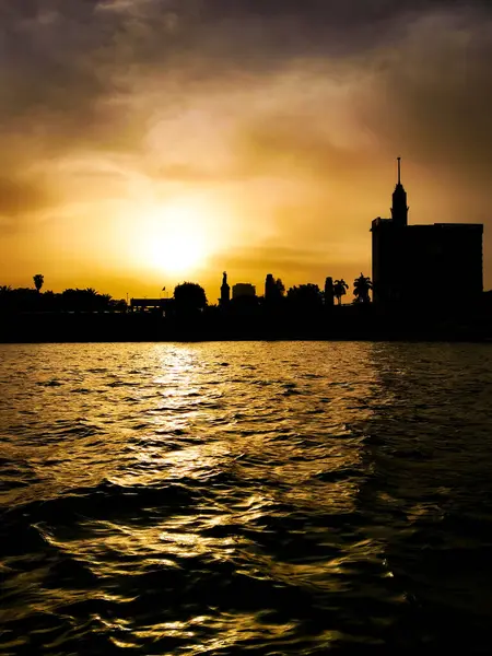 Черный силуэт реки и города на закате. — стоковое фото