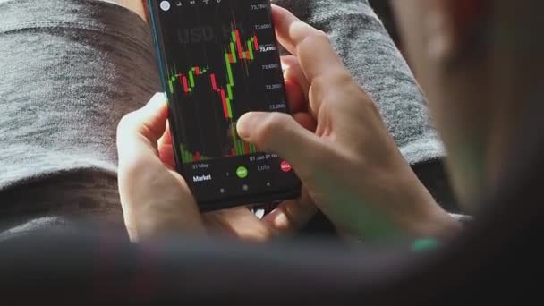 Um investidor verifica a dinâmica no valor das ações em uma tela de smartphone. — Vídeo de Stock