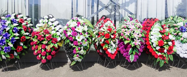 The funeral wreaths are made of plastic flowers.