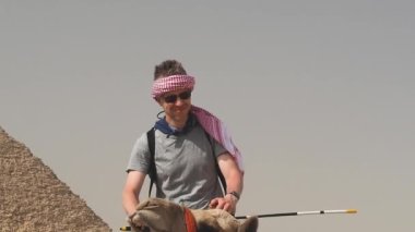 Khafre piramidinin arka planına karşı eyer üzerinde bir deve üzerinde turist