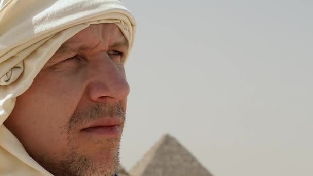 A cabeça de um homem em um lenço perto das pirâmides de giza — Vídeo de Stock