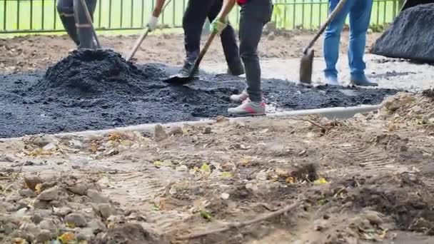 Pracovníci s lopatami vyrovnávající čerstvý asfalt podél nové pěšiny. — Stock video