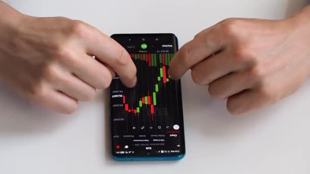 Un investitore controlla la dinamica del valore delle azioni sullo schermo di uno smartphone. — Video Stock