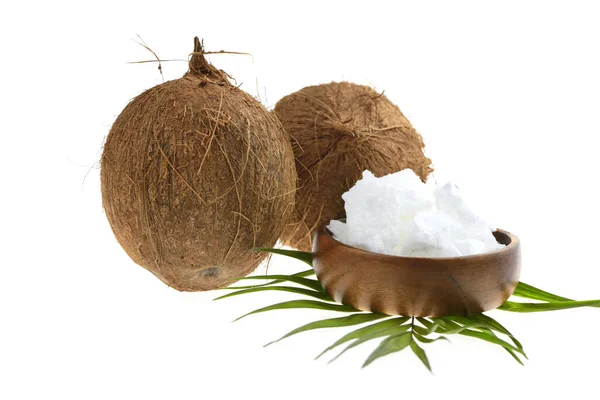 Organiczny olej kokosowy. Olej kokosowy w drewnianej filiżance i owoce kokosowe z zielonym liściem palmy na białym tle — Zdjęcie stockowe