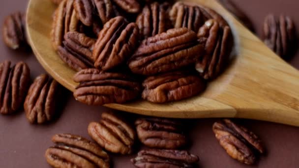 Pecan nut close-up em colher de madeira em fundo marrom brilhante.Gorduras saudáveis. Ingrediente da dieta keto — Vídeo de Stock