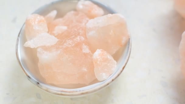 Růžová himalaya kousky soli zblízka v šedém poháru na světle mramorovém pozadí.Růžová krystalová sůl — Stock video