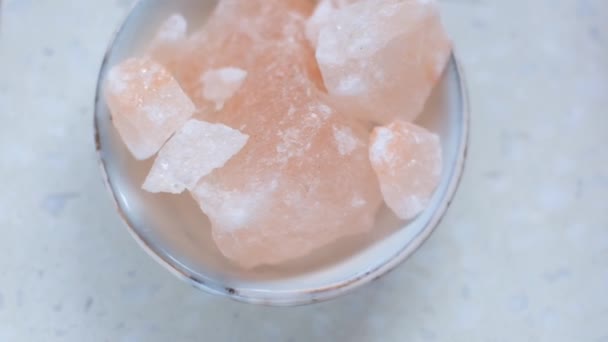 Růžové himálajské kousky soli zblízka v šedém poháru na mramorovém pozadí.Růžový krystal soli — Stock video