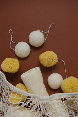 Sıfır atık kavramı. Kahverengi zemin üzerine kurulmuş doğal hijyen ve temizlik ürünleri. Lif süngeri ve süngerimsi konnyaku pamuk bej bir çantada. Atık içermeyen akıllı tüketim konsepti..