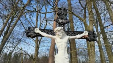 Katoliklik ve Hıristiyanlık kavramı. Dini sembol. Haç ve İsa heykeli bahar ormanı arka planında. Paskalya Dini Sembolü