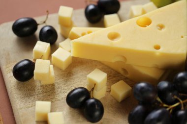 Maasdamer peyniri. Peynir maasdam parçası ya da ahşap tahtada kahverengi zeminde maasdamer. Sert peynir. Süt ürünleri. Sağlıklı ve lezzetli atıştırmalıklar. Maasdam peyniri.