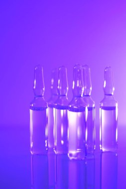 Tıp ve farmakoloji konsepti. Aşı ampulleri. şeffaf ampuller mor ışığa ayarlandı. Biyoteknoloji ve bilim. Enjeksiyon için çözeltiler. Sağlık ve güzellik.