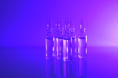 Tıp ve farmakoloji konsepti. Aşı ampulleri. Camdan şeffaf ampuller mor ışıkta ayarlandı. Biyoteknoloji ve bilim. Enjeksiyon için çözelti. Sağlık ve güzellik.