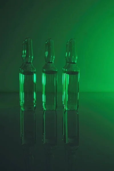 Biotechnology and Science. Medicine and Pharmacology concept.transparent ampoules set in green light.Organic natural cosmetics concept.Ampoules with solution for injection.Health and beauty