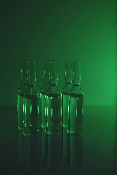 Biotechnology and Science. Medicine and Pharmacology .Glass transparent ampoules set in green light.Organic natural cosmetics concept.Ampoules with solution for injection.Health and beauty