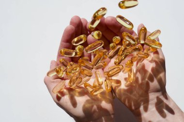  Balık yağı kapsülleri. Omega asitler. Beslenme takviyeleri. Omega-3 Şişko Acid. balık yağı jelatin kapsülleri beyaz bir arka planda erkeklerin elleri üzerinde yükselmeyi sağlar. Sağlıklı yiyecek ve yaşam tarzı..