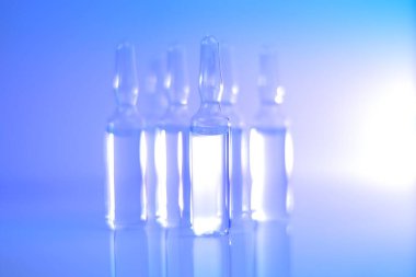 Tıp ve Eczacılık. Biyoteknoloji ve Bilim. Açık mavi ve mor tonlarda şeffaf ampuller. Enjeksiyon için çözünürlükle birlikte. Sağlık ve güzellik.