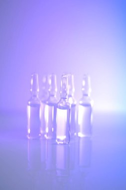Tıp ve Eczacılık. Biyoteknoloji ve Bilim. Açık mavi ve mor tonlarda şeffaf ampuller. Enjeksiyon için çözeltilerle dolu. sağlık ve güzellik. Organik kozmetik.