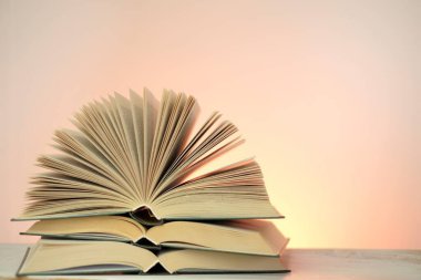 Kitap ve edebiyat okumak. Açık pembe arkaplan üzerine kurulu kitap yığınları. Eğitim ve eğitim kavramı. Kitap sayfalarını kapat. Öğrenme ve bilgi.