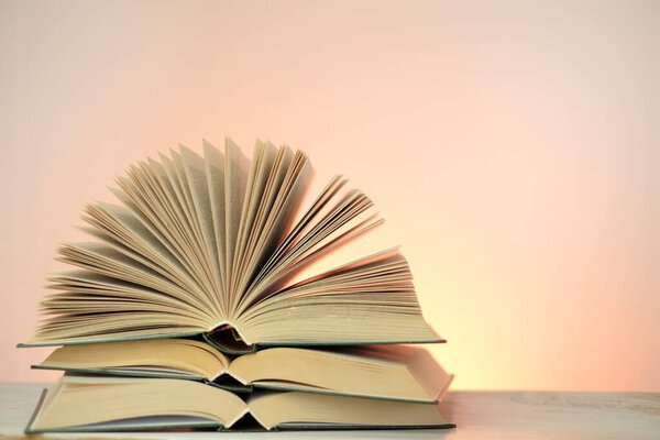 Reading books and literature.Open books stack set on a light pink background. Study and education concept. Close-up book pages.Learning and knowledge. High quality photo