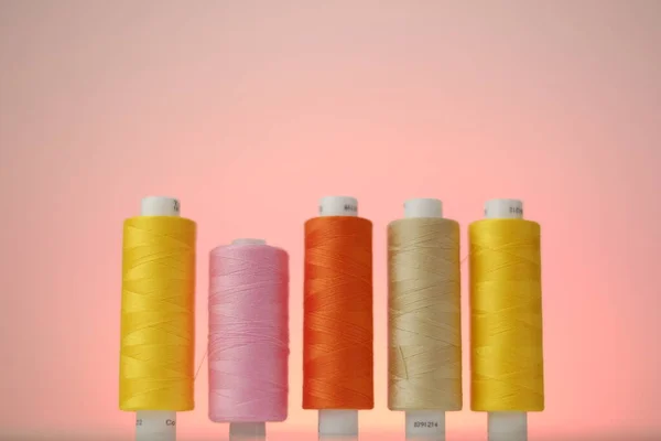 Sewing threads.Multicolored threads set. Yellow, orange and pink threads on a pink background. Hobby and handicraft concept — Stock Photo, Image