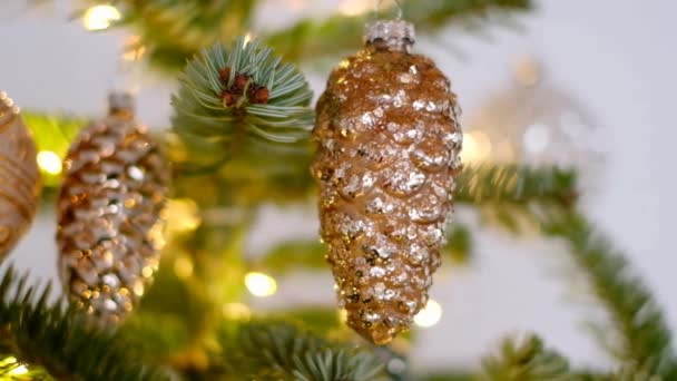 Karácsonyi ünnepi háttér. Karácsonyi labdák meghatározott arany tónusok és egy ragyogó koszorú egy karácsonyfa egy könnyű háttér — Stock videók