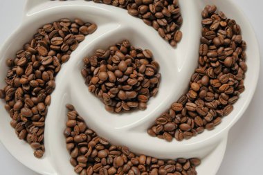 Coffee beans in textured plate. Roasted coffee beans.Morning traditional drink. Coffee beans texture.Invigorating drink ingredients clipart