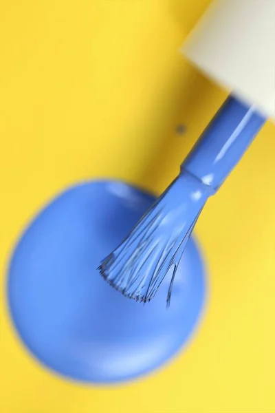 Nail polish. Blue drops of nail polish and brush on bright yellow background — Stock Photo, Image