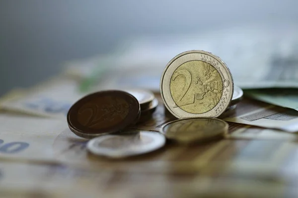 Dinero. Monedas en euros y billetes en euros sobre un fondo verde borroso. .. Dos monedas de euro. Moneda europea. Finanzas y ahorros. — Foto de Stock