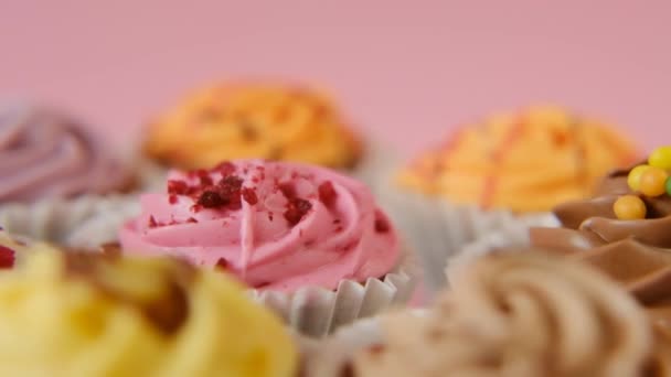 Crème cupcakes.Fruit en bessen taarten op een roze achtergrond. Gesorteerde zoete tafel. Snoep en desserts. Rotatie. — Stockvideo