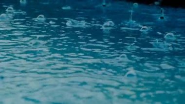 Su damlaları. Su kabarcıkları ve damla dokusu. Su yağmur damlalarıyla mavidir. Yavaş çekim.