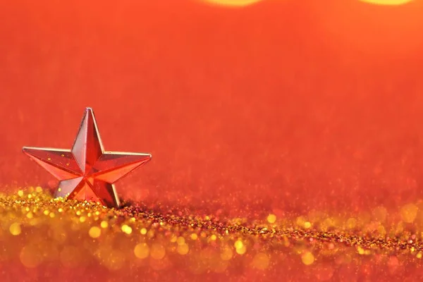 Natal e Ano Novo fundo. Estrela vermelha em brilho ouro brilhante em um fundo borrado vermelho.Natal papel de parede feriado — Fotografia de Stock