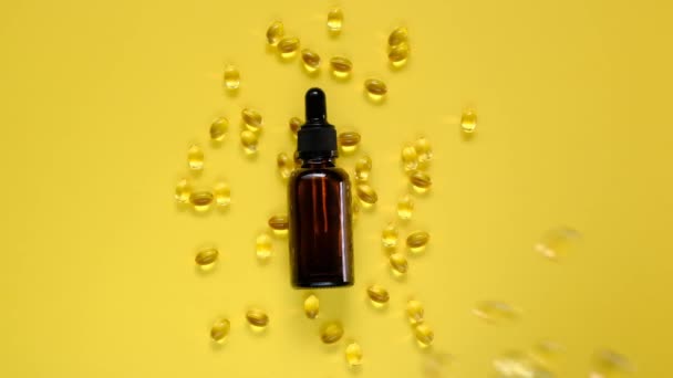 Vitamina D. Estratto di olio e gelatina capsule trasparenti con vitamina D su un fondo giallo brillante. Vitamine e minerali. Integratori alimentari. Flacone di vetro marrone e capsule di gelatina cadenti. Lento. — Video Stock