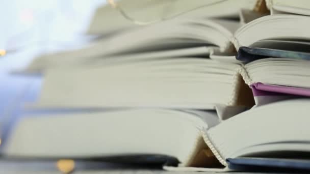 Books stack close-up and garland on blurred blue background.Winter books. — Stock Video