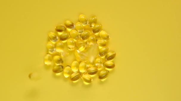 Vitamin D gelatin capsules on a bright yellow background.falling capsules with vitamin D. Vitamins and minerals.Food supplements. — Stock Video