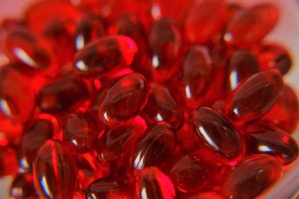 Krill oil capsules background.omega fatty acids. Natural supplements and vitamins.Red capsules with krill oil