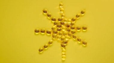 D vitamini kapsüllerinden yapılmış D vitamini işareti. Parlak sarı arka planda D vitamini içeren şeffaf jelatin kapsüller. Vitaminler ve mineraller. Yiyecek takviyesi..