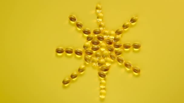 Vitamine D. Zonneteken gemaakt van vitamine D capsules. gelatine transparante capsules met vitamine D op een felgele achtergrond.Vitaminen en mineralen. Voedingssupplementen. — Stockvideo