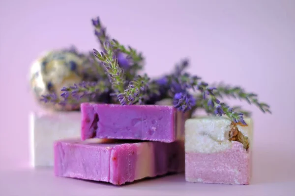 Lavendelseife und Badebomben, Lavendelzweige auf hellviolettem Hintergrund. Veganes Kosmetikkonzept. Biologische Kräuterkosmetik mit Lavendelextrakt — Stockfoto