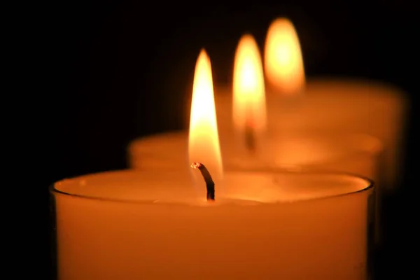 Llama de vela. conjunto de velas blancas. Velas encendidas en la oscuridad —  Fotos de Stock