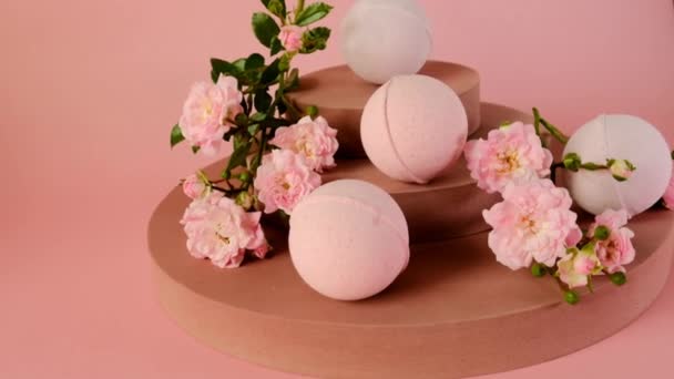 Bombes de bain avec extrait de rose. bombes de bain et fleurs roses roses sur socle bordeaux sur un fond rose pâle. Cosmétiques bio végétaliens éco. Cosmétiques naturels bio à l'extrait de rose. bain de fleurs — Video