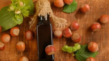 Fındık yağı. Organik vegan taze fındık yağı. Cam şişe, yeşil ve kahverengi olgun fındıklar ahşap kahverengi bir masada..