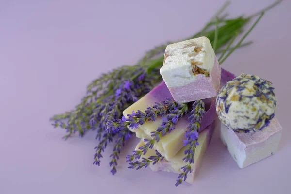 Lavendel Bad Bommen en Zeep, lavendel bloemen op een licht paarse achtergrond.Spa en aromatherapie. Biologische cosmetica met lavendelextract.Schoonheid en ontspanning — Stockfoto