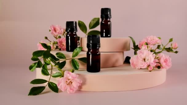 Rose essential oil on a light pink background.Organic essential bio oil. Glass brown bottles set, pink roses on pink catwalks — Stock Video
