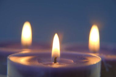 Yanan mumlar. Mum alevi. Karanlıkta mavi ve beyaz mumlar. Din sembolü. Mumlar arka planda. Mavi arkaplanda mavi mumlar.