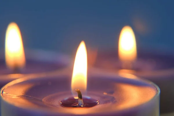 Burning candles.Candle flame in the dark.Religion symbol. Candles background.Blue candles on blue background