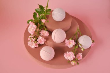 Gül özlü banyo bombaları. Pembe banyo bombaları ve pembe gül çiçekleri pembe arka planda. Organik vegan kozmetik ürünleri. Gül özlü doğal kozmetik ürünleri. Çiçek Banyo Bombaları.