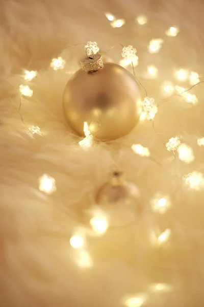 Χριστουγεννιάτικο φόντο με λαμπερό γιρλάντα και μπάλες σε μπεζ γούνα σε ζεστά χρώματα. Χειμερινές διακοπές φόντο.Ζεστό φόντο χειμώνα. — Φωτογραφία Αρχείου
