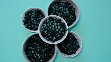 Yosun tabletleri. Vejetaryen Omega 3. Yeşil arka planda, fincanlarda, Omega-3 alternatif kaynağıyla. Bitki kaynaklı amino asit ve omega 3..
