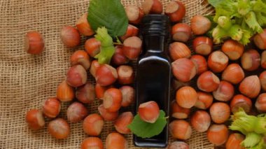 Fındık yağı. Cam şişe, yeşil ve kahverengi fındıklı ahşap kahverengi masa. Organik vegan taze fındık yağı..