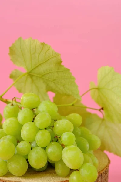 Uva. Un racimo de uvas verdes con hojas sobre un fondo rosado.Frutos naturales orgánicos —  Fotos de Stock